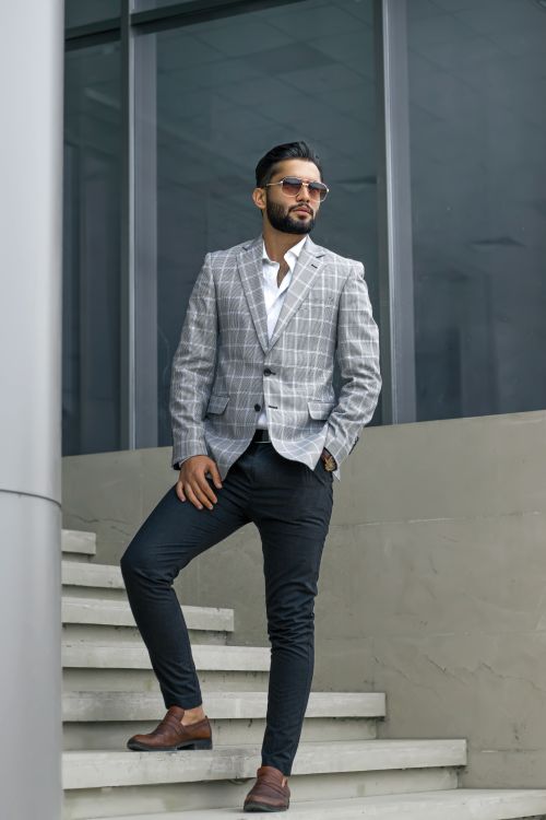 Free Confident man in plaid suit posing by modern architecture, embodying urban style and elegance. Stock Photo