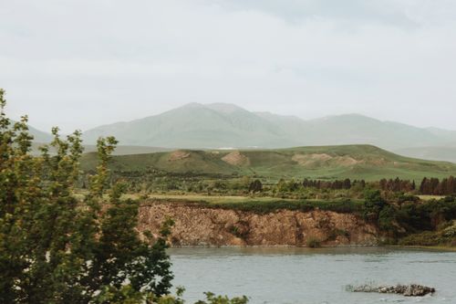 Free Peaceful view of mountains, river, and lush greenery under a clear sky. Stock Photo