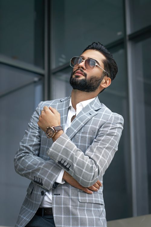 Free Confident man in plaid suit and sunglasses posing outside an office building. Stock Photo