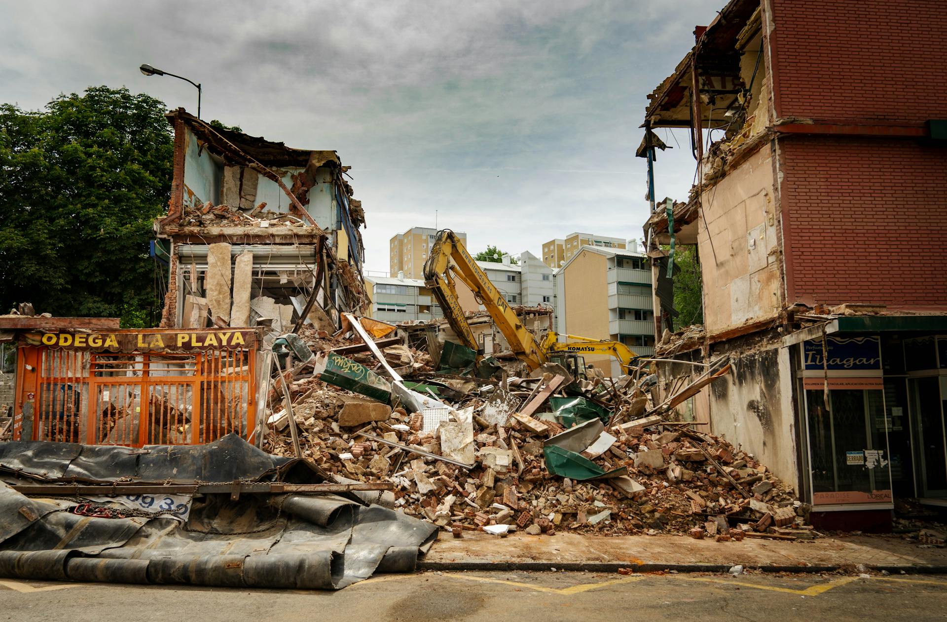 Dramatic demolition of urban building with rubble and excavator at work.