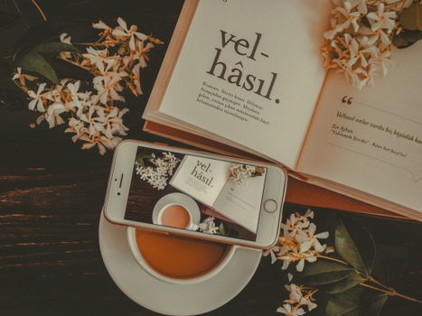 Artistic flat lay of a book, coffee, and flowers with warm tones. Perfect for cozy and aesthetic settings.