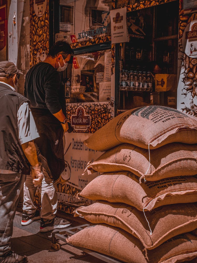 Men Standing In A Queue To The Shop By The Heap Of Textile Bags