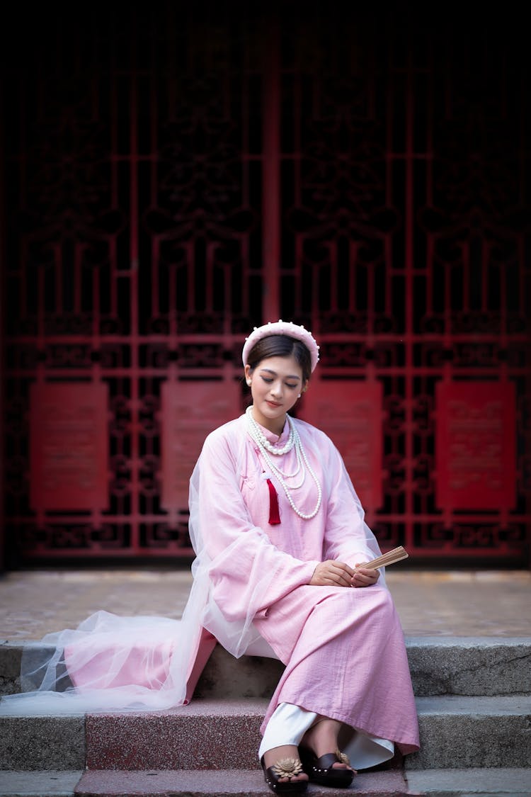 A Woman Wearing Pink Dress Sitting On The Stairs