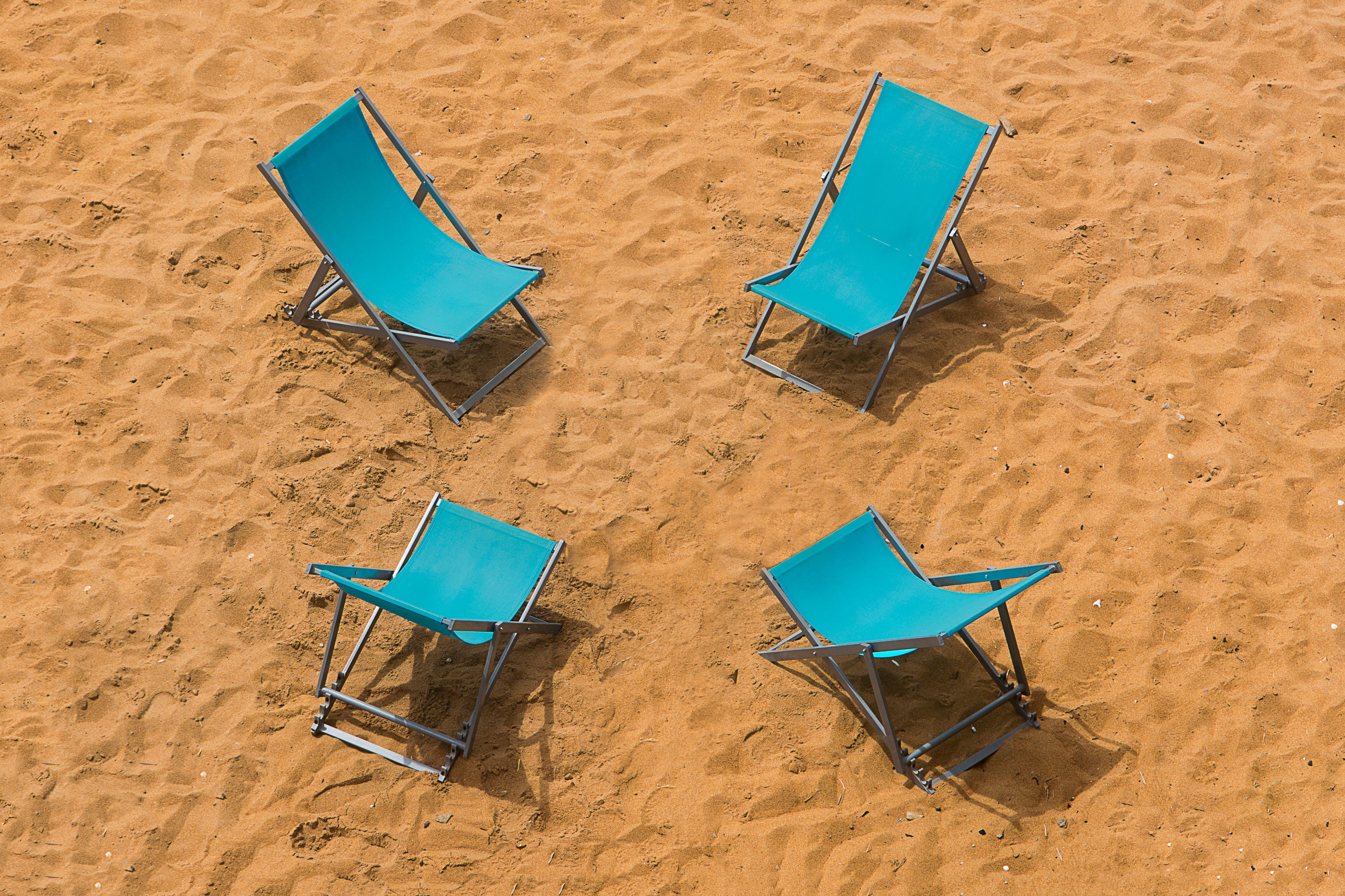Aerial view of blue beach chairs arranged on a sandy shoreline, perfect for summer vibes.