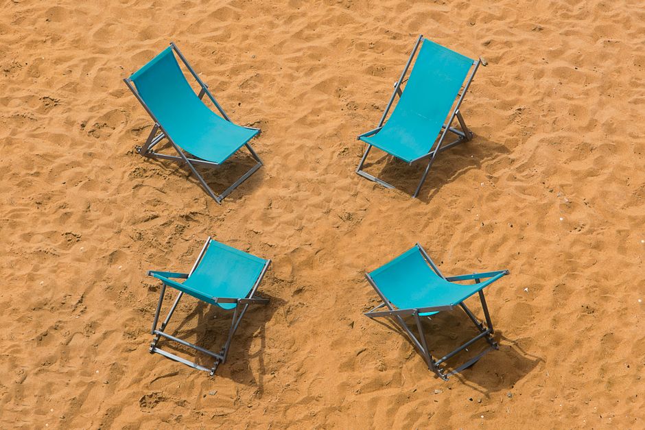 Aerial view of blue beach chairs arranged on a sandy shoreline, perfect for summer vibes.