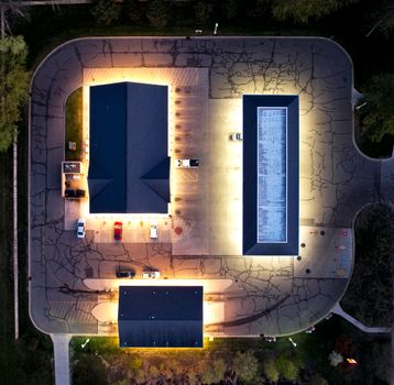 Drone image of lit buildings and parking lot in River Falls at night.