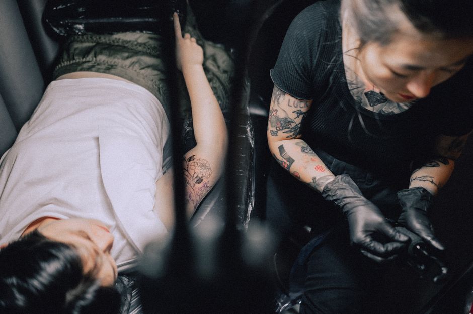 Tattoo artist creating a new tattoo for a client in a professional studio environment. Tattoo artist creating a new tattoo for a client in a professional studio environment.
