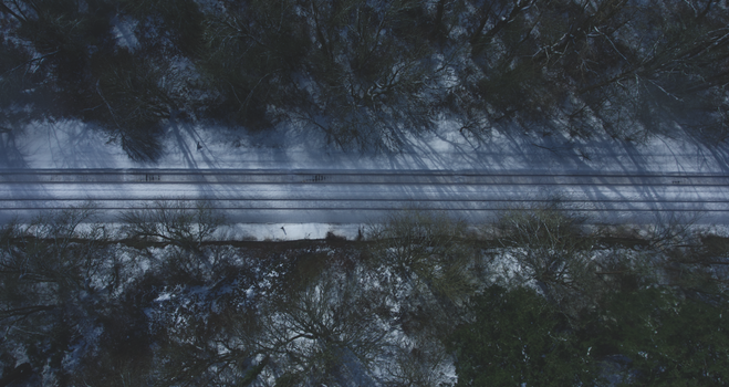 Aerial view of snowy train tracks through a winter forest landscape in Washington, USA.