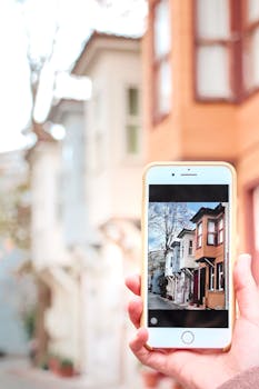 A smartphone capturing a close-up photo of urban architecture on a bright day.