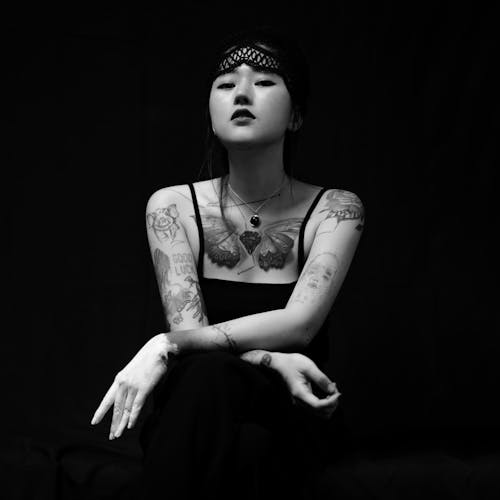 Grayscale Photo of a Woman with Tattoos Looking at the Camera