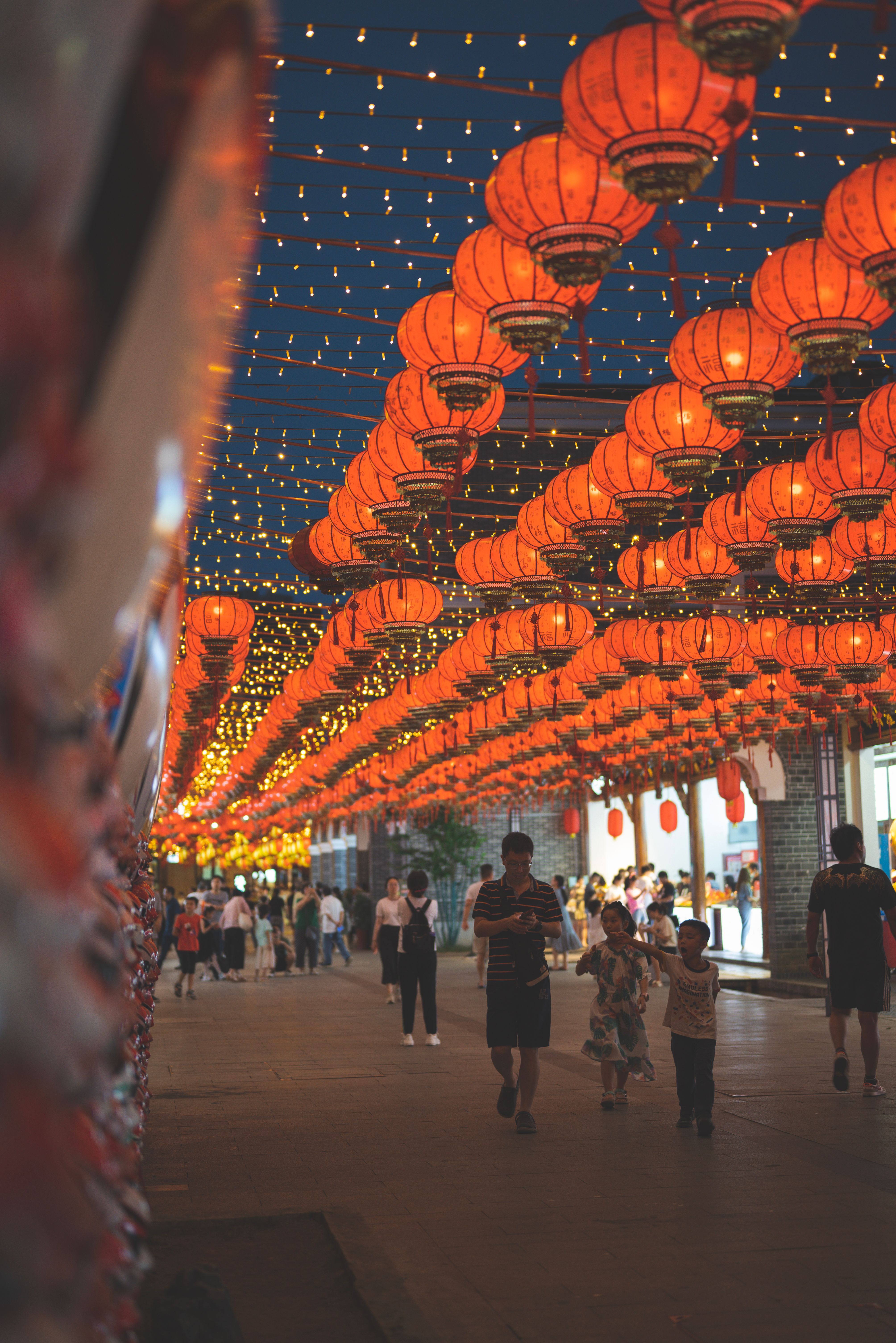 A bustling street lit with red Chinese lanterns during a vibrant festival evening, capturing lively celebration vibes.