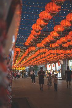 A bustling street lit with red Chinese lanterns during a vibrant festival evening, capturing lively celebration vibes.