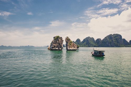 Free Halong Bay's iconic limestone formations and a traditional boat under a clear sky. Stock Photo