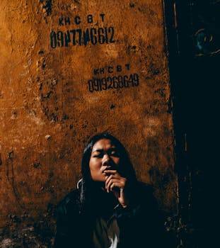 在越南河内，一个女人靠在纹理墙壁上的戏剧性肖像