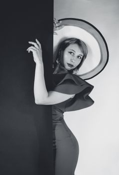 Elegant black and white portrait of a woman in vintage fashion with a stylish hat.