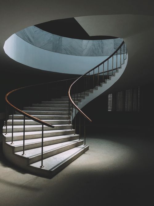 Free Empty spiral steps with metal railings in contemporary spacious building hallway in dark Stock Photo