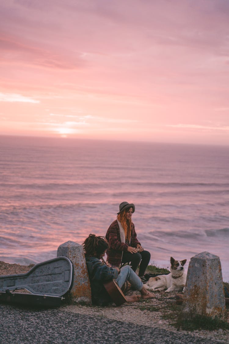 Woman, Man And Dog On Sea Shore At Sunrise