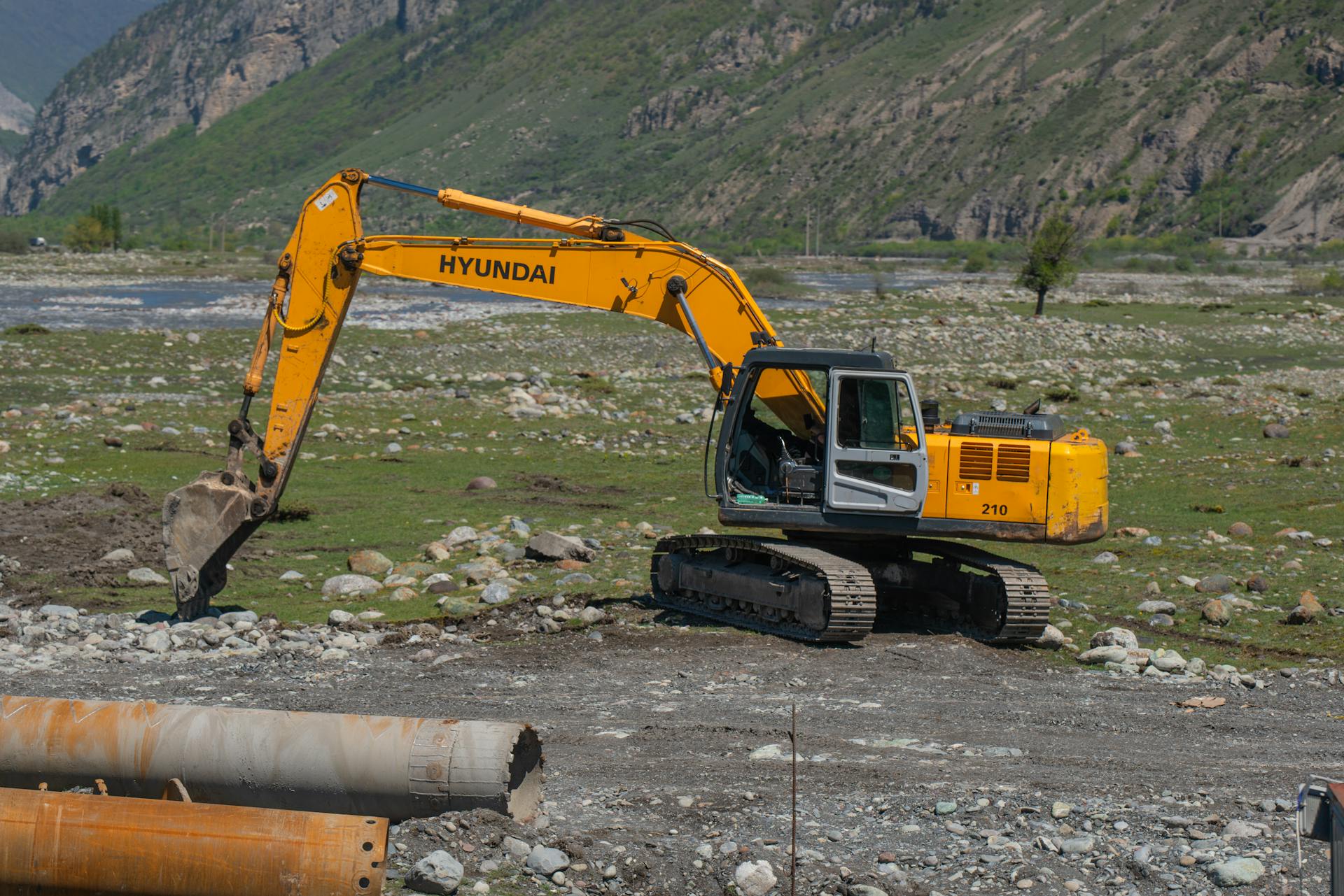 Yellow excavator operating in a rocky mountain landscape, ideal for industry themes.