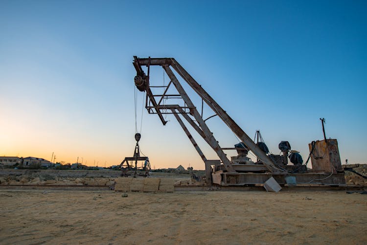 A Rusty Broken Crane Equipment On Sand