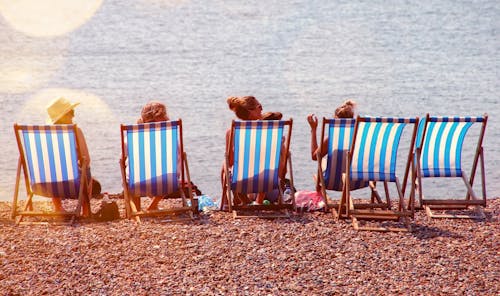 Free Four People On Lounge Chairs Near The Beach Stock Photo