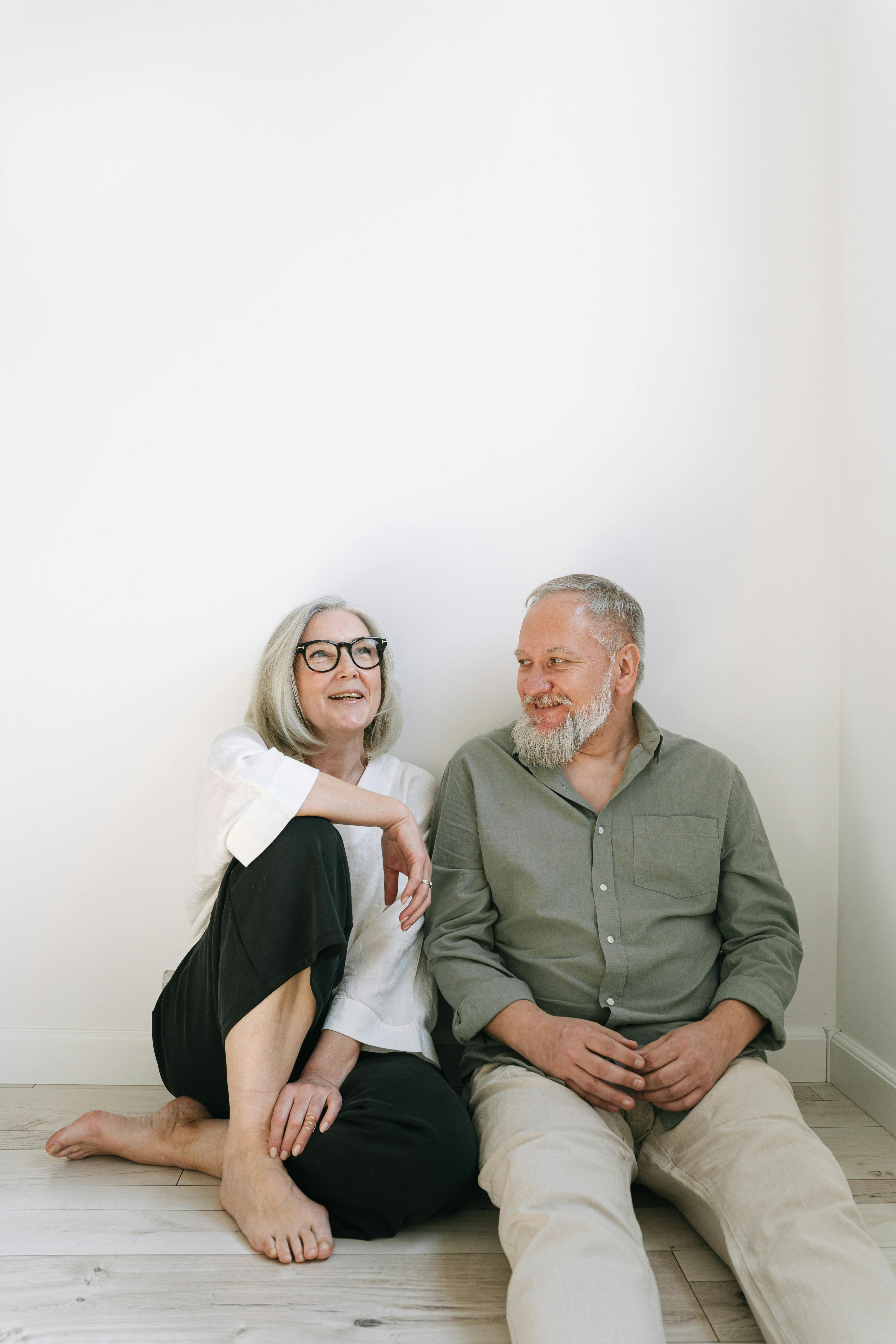 Happy senior couple sitting on the floor, sharing a joyful moment indoors.