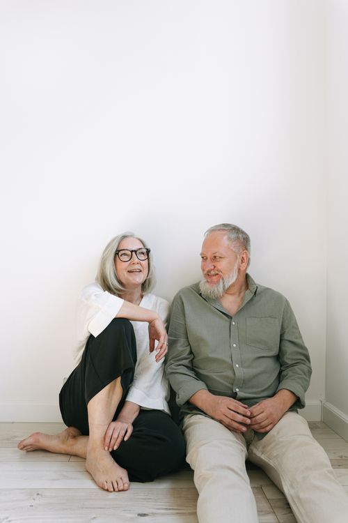 Free Happy senior couple sitting on the floor, sharing a joyful moment indoors. Stock Photo