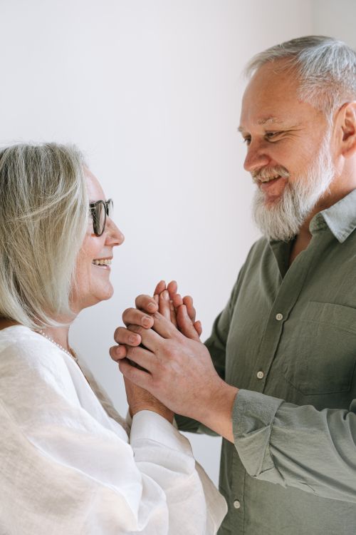 Free A happy elderly couple smiling and holding hands indoors, exuding warmth and love. Stock Photo