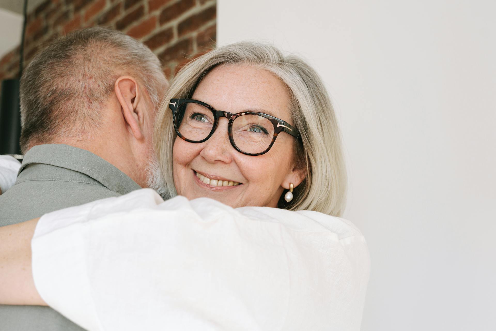 Happy senior couple sharing an affectionate hug indoors, highlighting love and contentment.