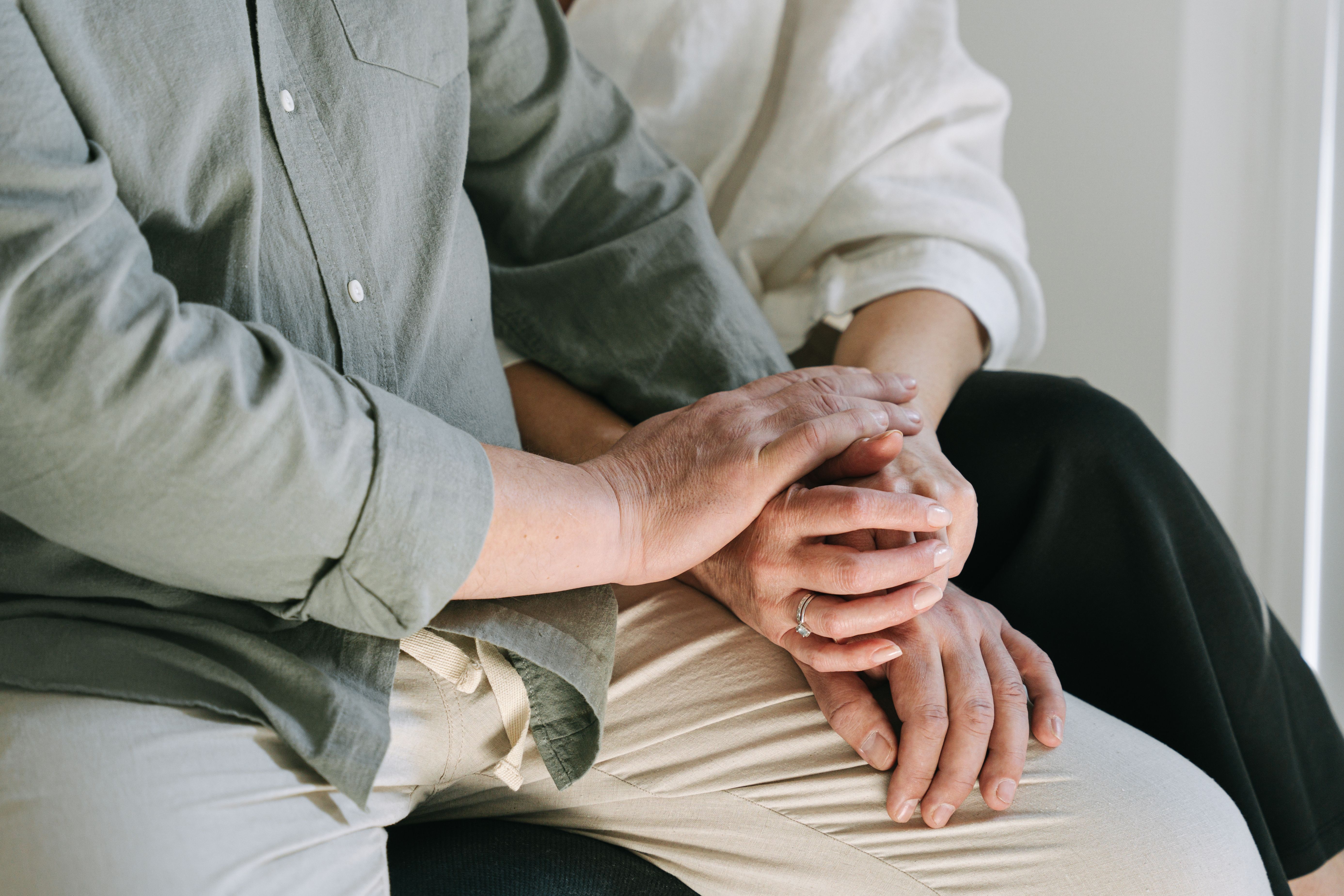 A couple resting their hands together in a quiet moment of support