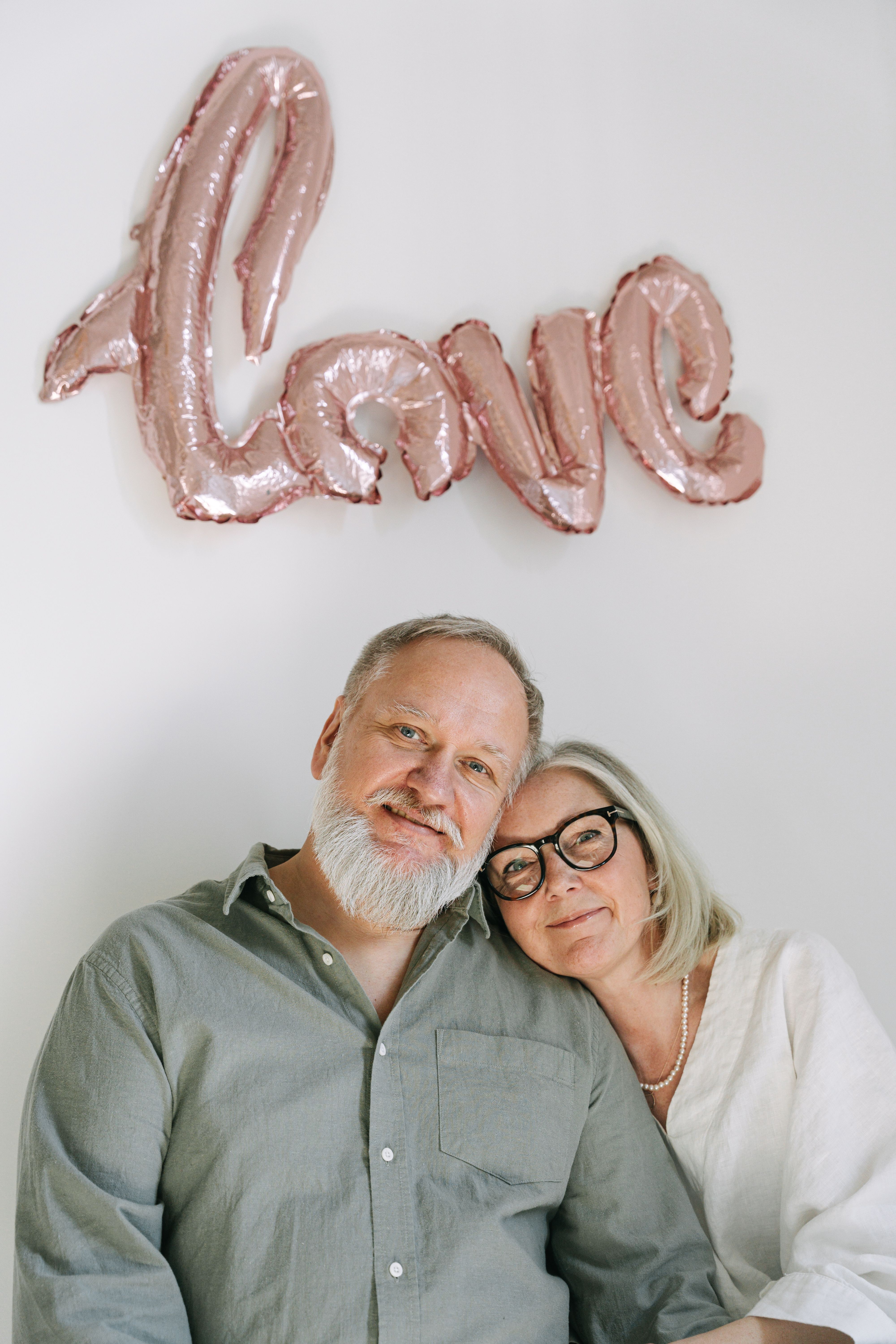 Senior couple affectionately posing with a love balloon symbolizing their relationship.