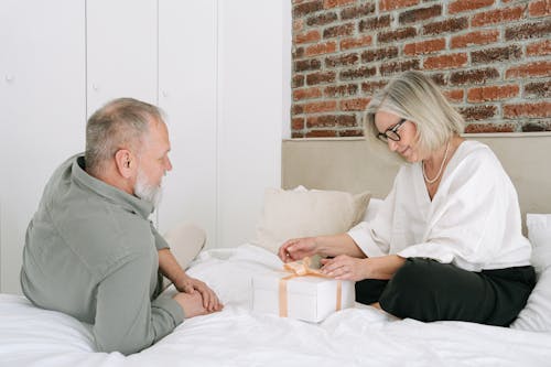 Free Elderly Woman Sitting on Bed Looking at a Gift Stock Photo