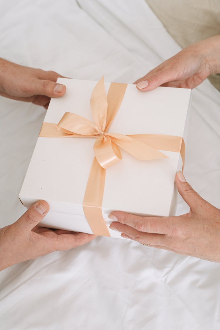 People Holding Box With Gold Ribbon