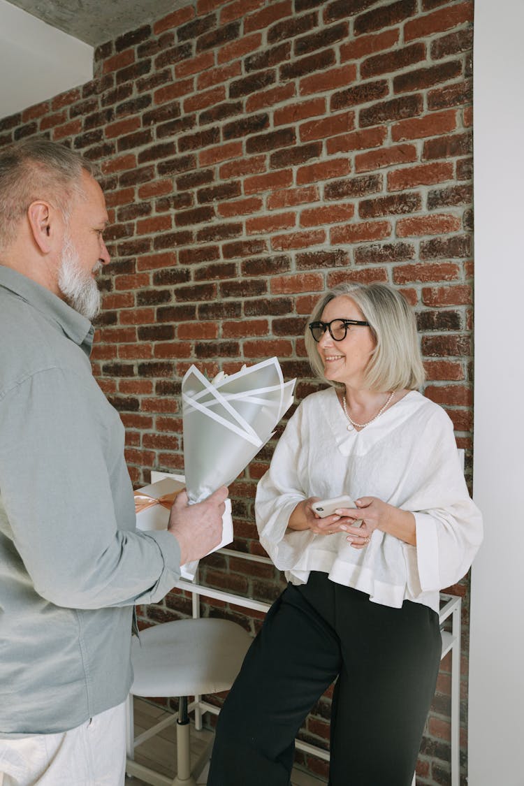 A Man Giving His Wife A Gift Box And A Bunch Flowers