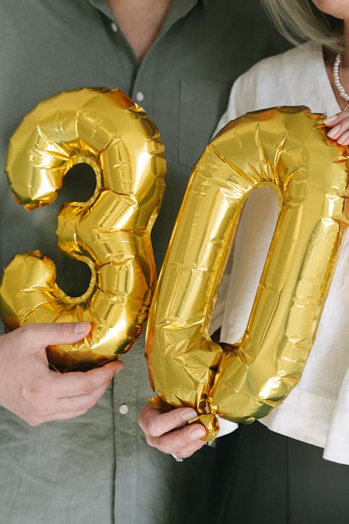 Person Holding Gold Inflatable Balloons