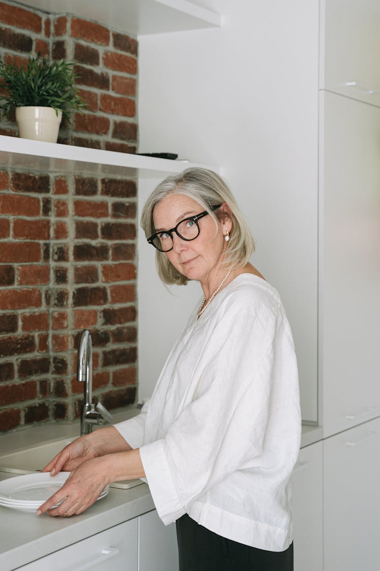 A Woman In White Long Sleeves Holding Plates