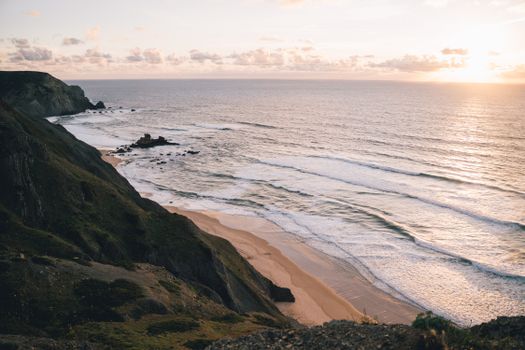 Breathtaking view of Portugal's rugged coastline at sunset, with waves crashing against the rocky shore.