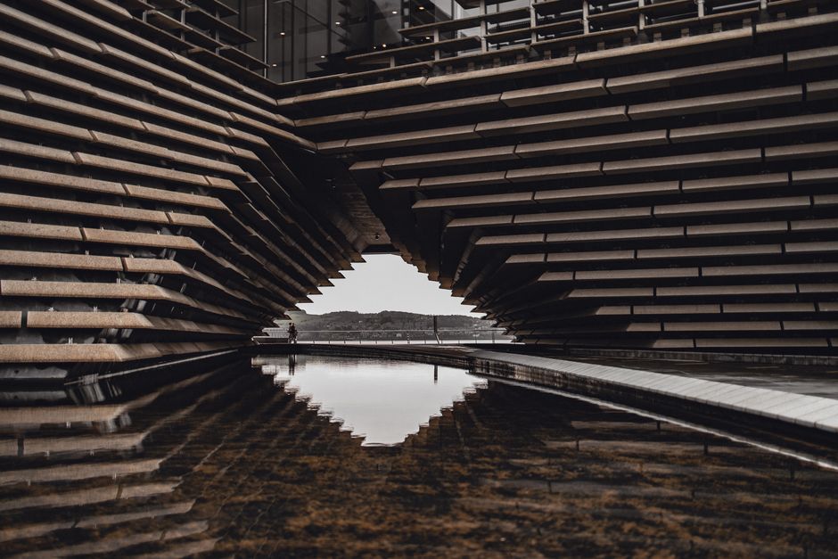Intricate modern design of the V&A Dundee with reflections in a pond, Scotland.