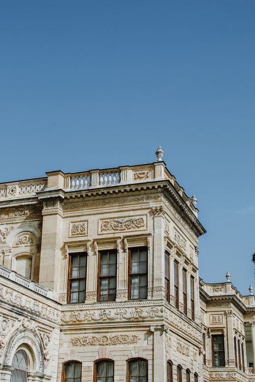 Free Low-angle view of a classic renaissance palace facade under a bright blue sky. Stock Photo