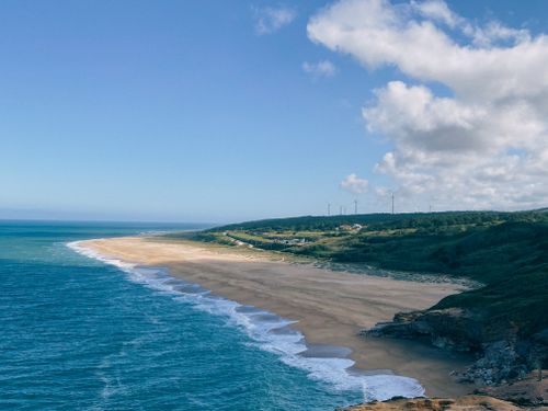Free Expansive beach and sea view at Nazaré, Portugal, with clear blue skies and gentle waves. Stock Photo