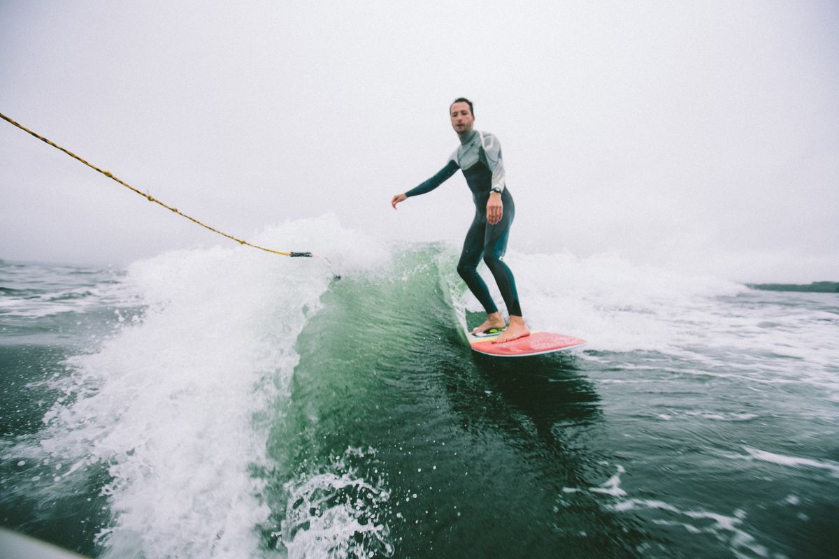 Wakesurfer riding the wave behind a boat on a lake