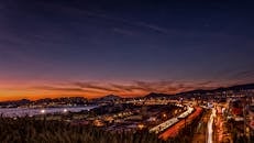 黄昏时分，城市展现出令人惊叹的景观，光路、山脉和发光的天际线尽收眼底