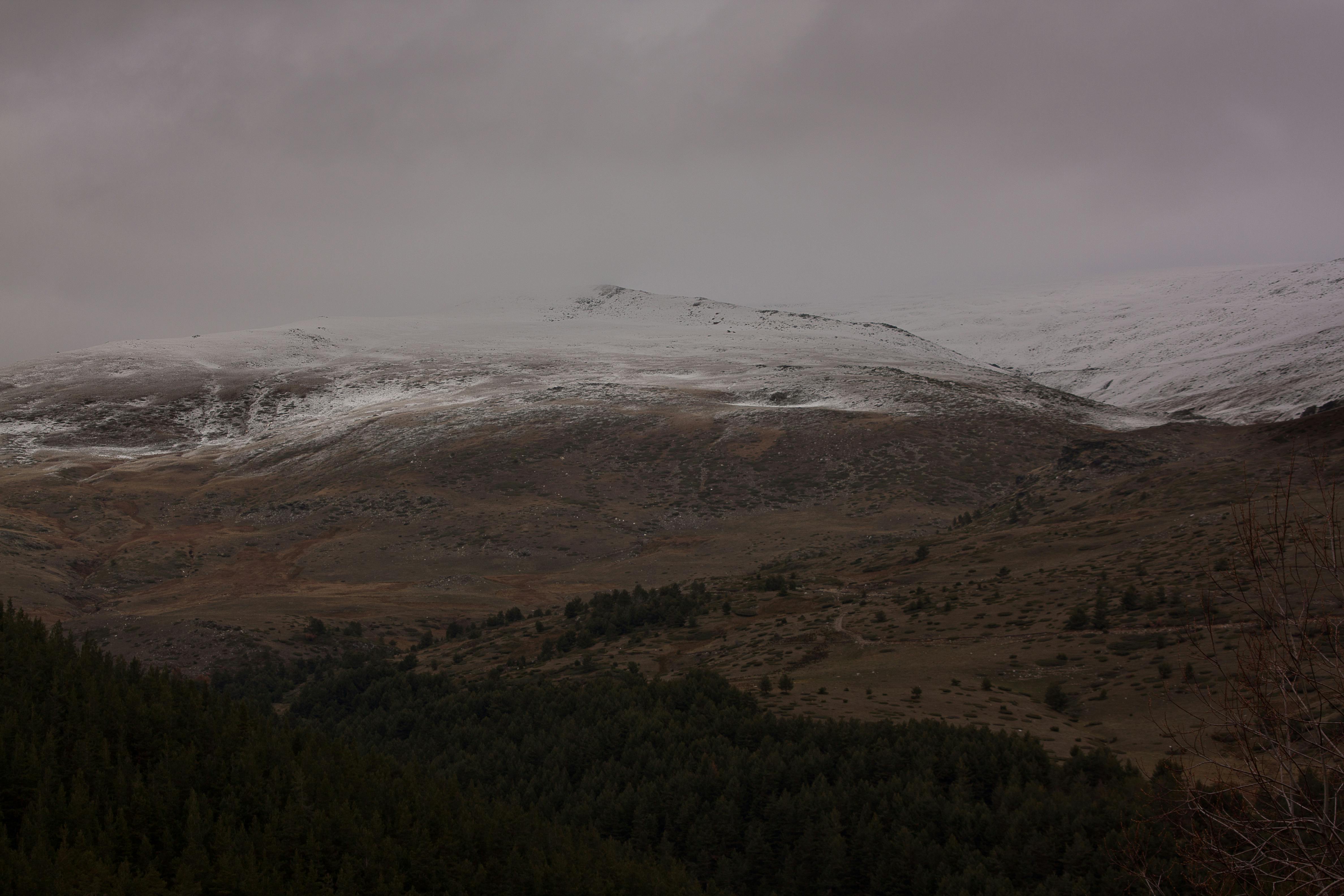 Prescription Goggle Inserts - Aerial view of snow-covered mountain under cloudy skies, showcasing nature's serene beauty.