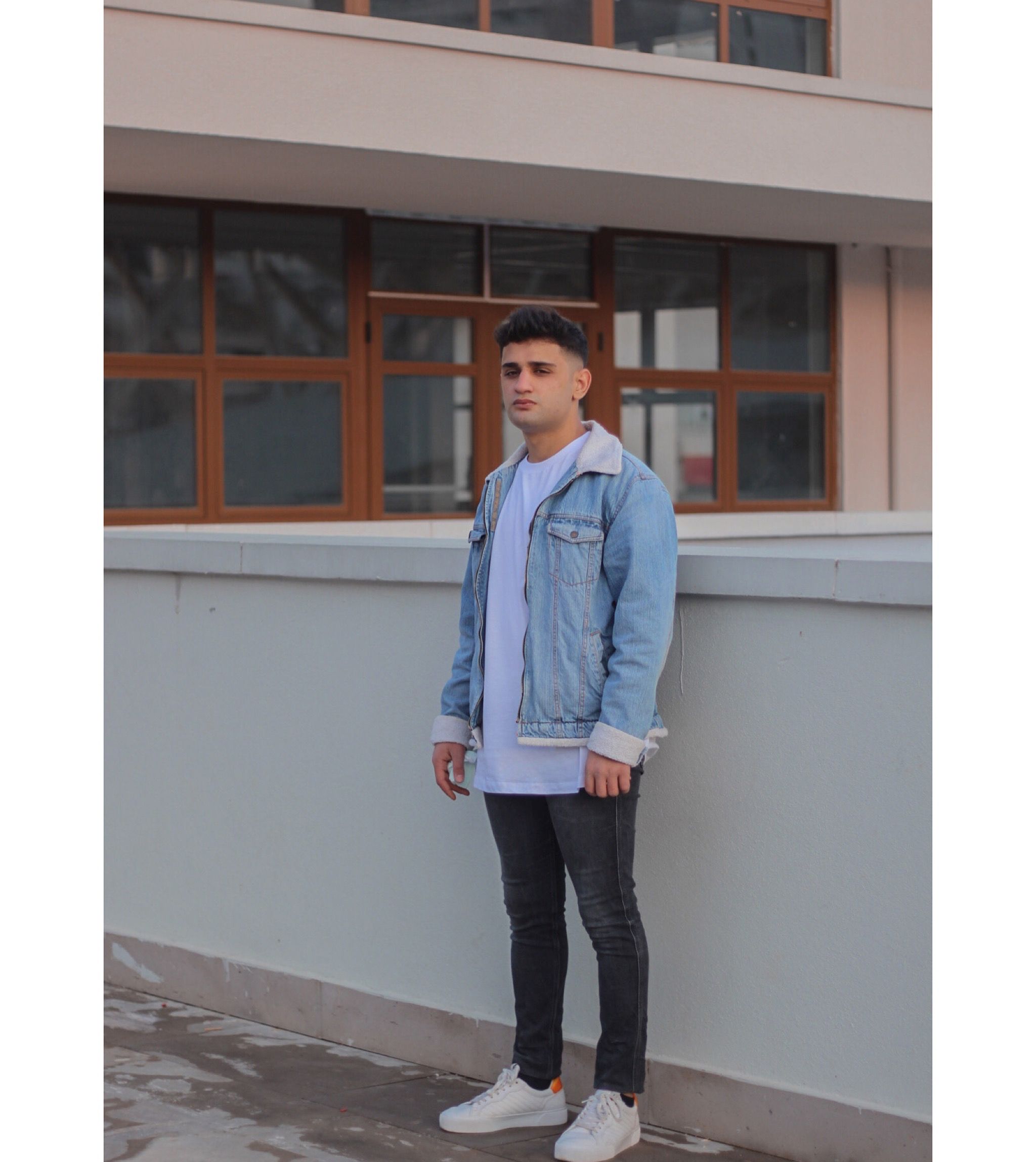 Man in Denim Jacket Standing Beside a Concrete Fence · Free Stock Photo