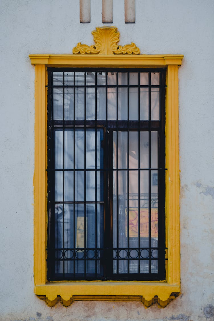 Black Metal Window Frame With Yellow Cornice On White Concrete Wall