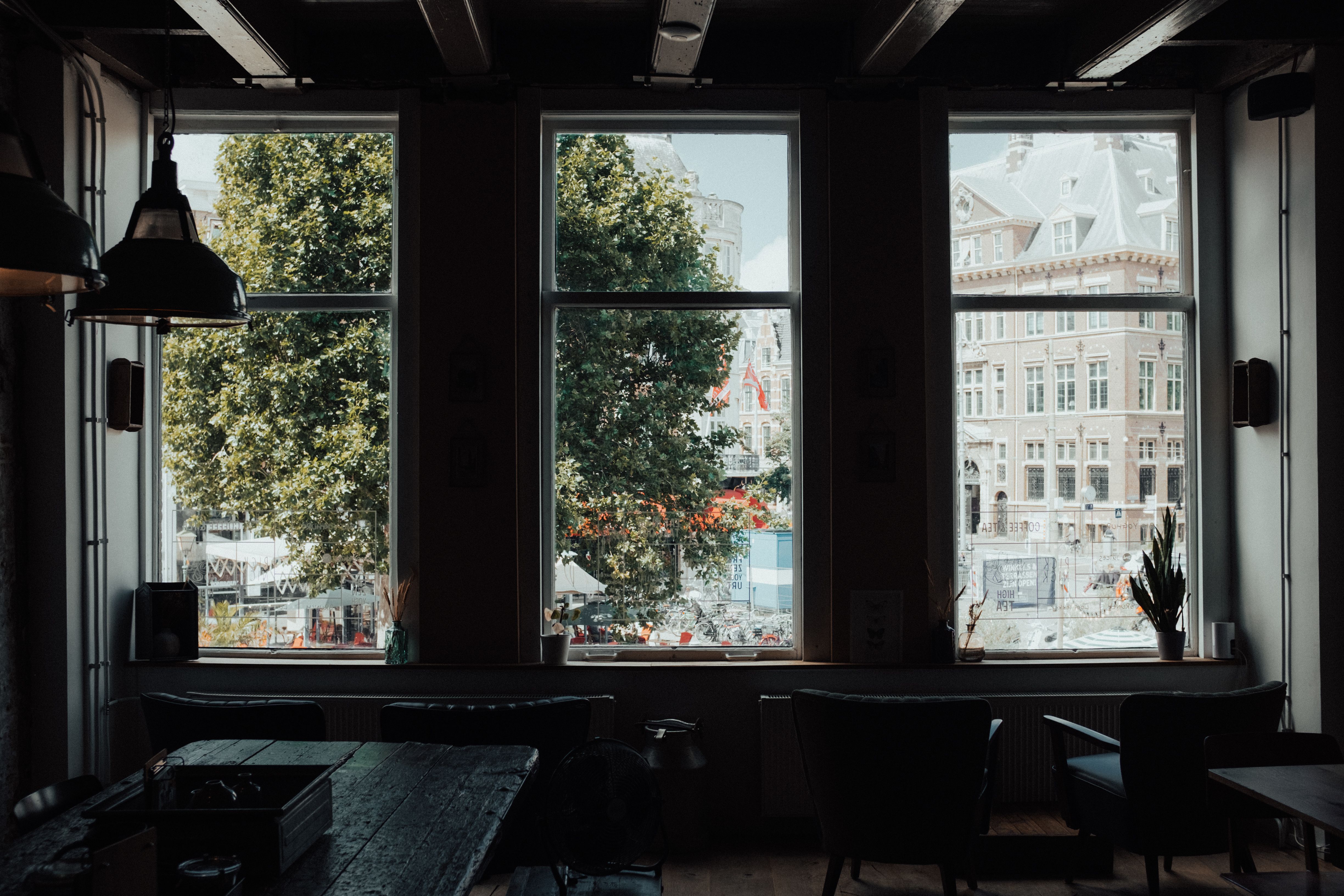 Interior view through large windows showing a historic European building and city life.
