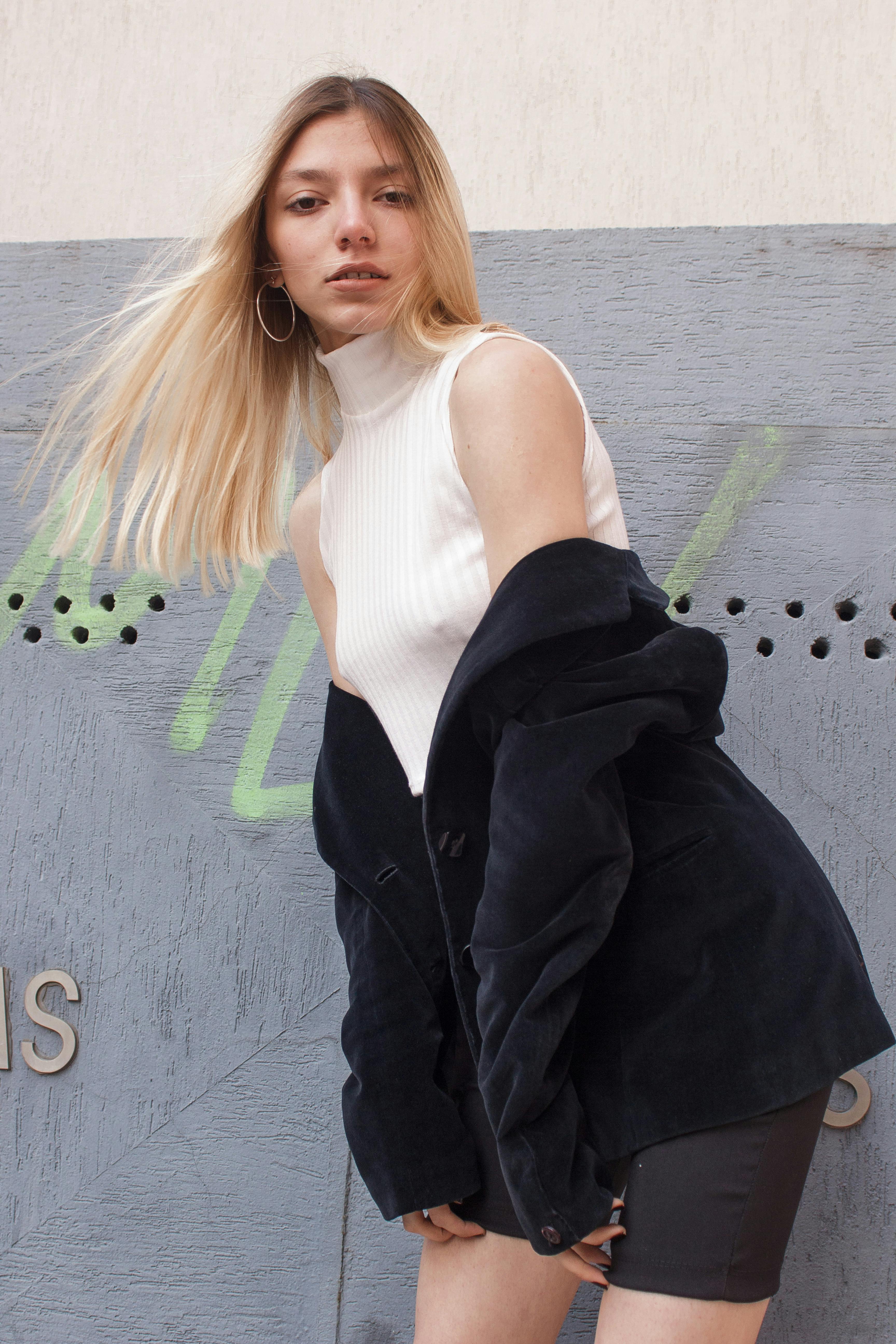 Portrait of a young woman posing in a trendy outfit against a textured wall.