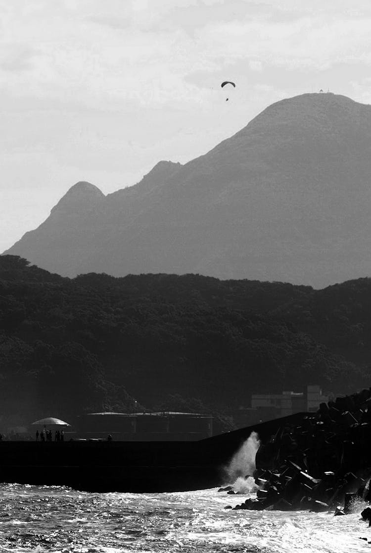 A Person Paragliding Near A Mountain And Sea