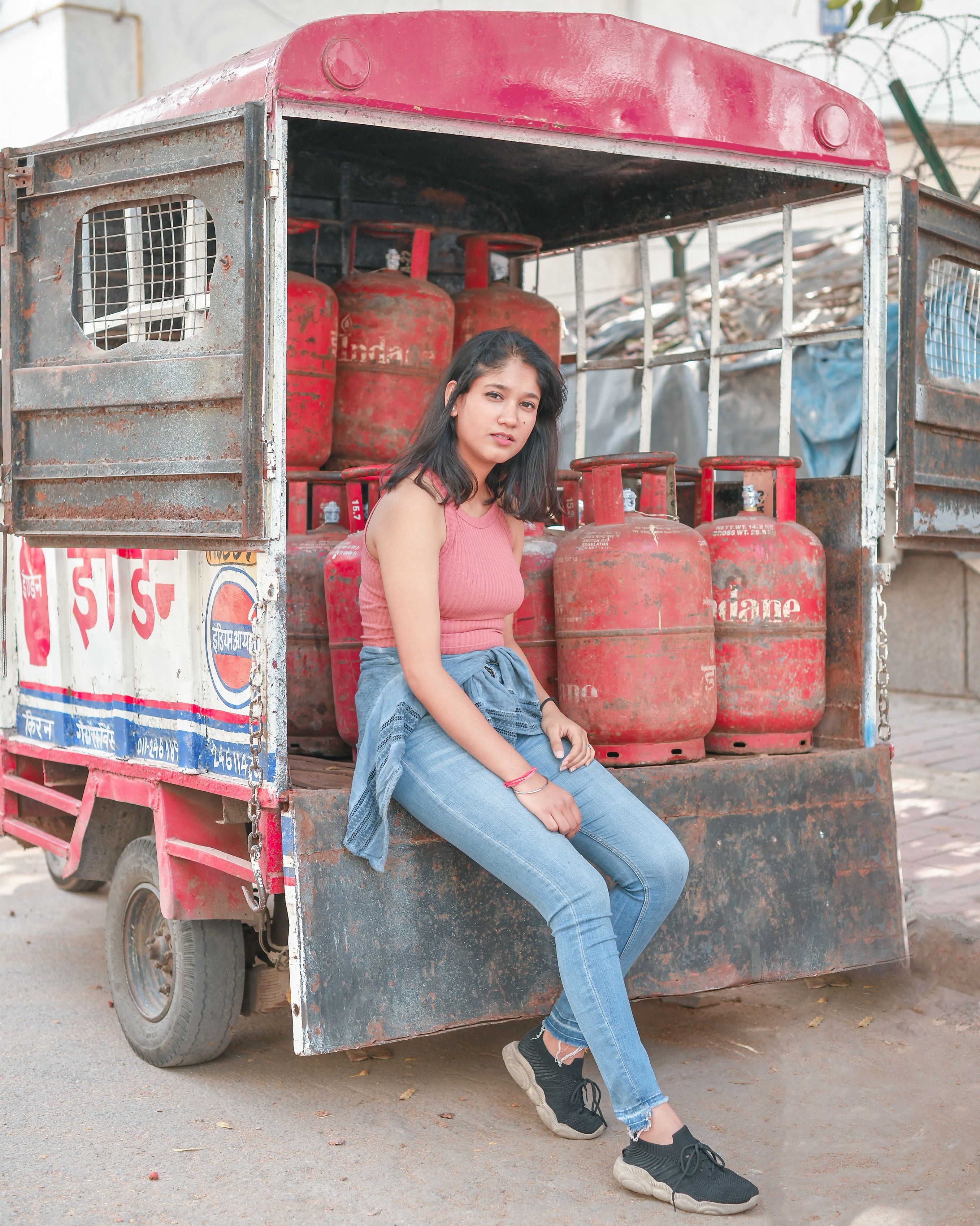A young woman sits on a truck with gas tanks in a casual outdoor setting.