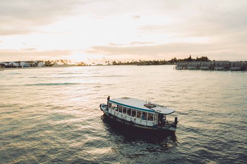 Free Passenger ship floating on rippling surface of seawater against shore with trees and buildings of coastal town on summer day Stock Photo