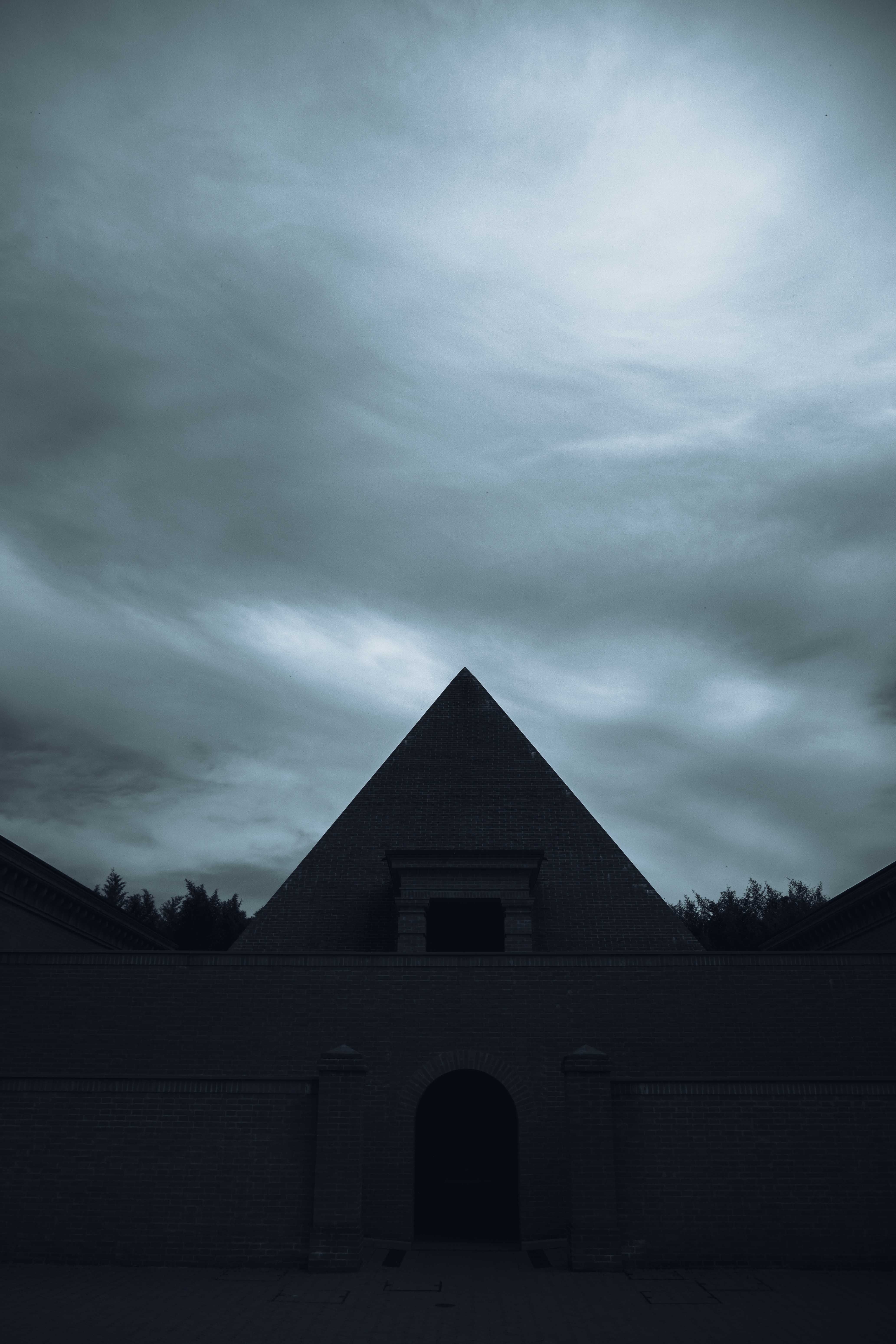 Old stone building with arched doorway under cloudy sky · Free Stock Photo